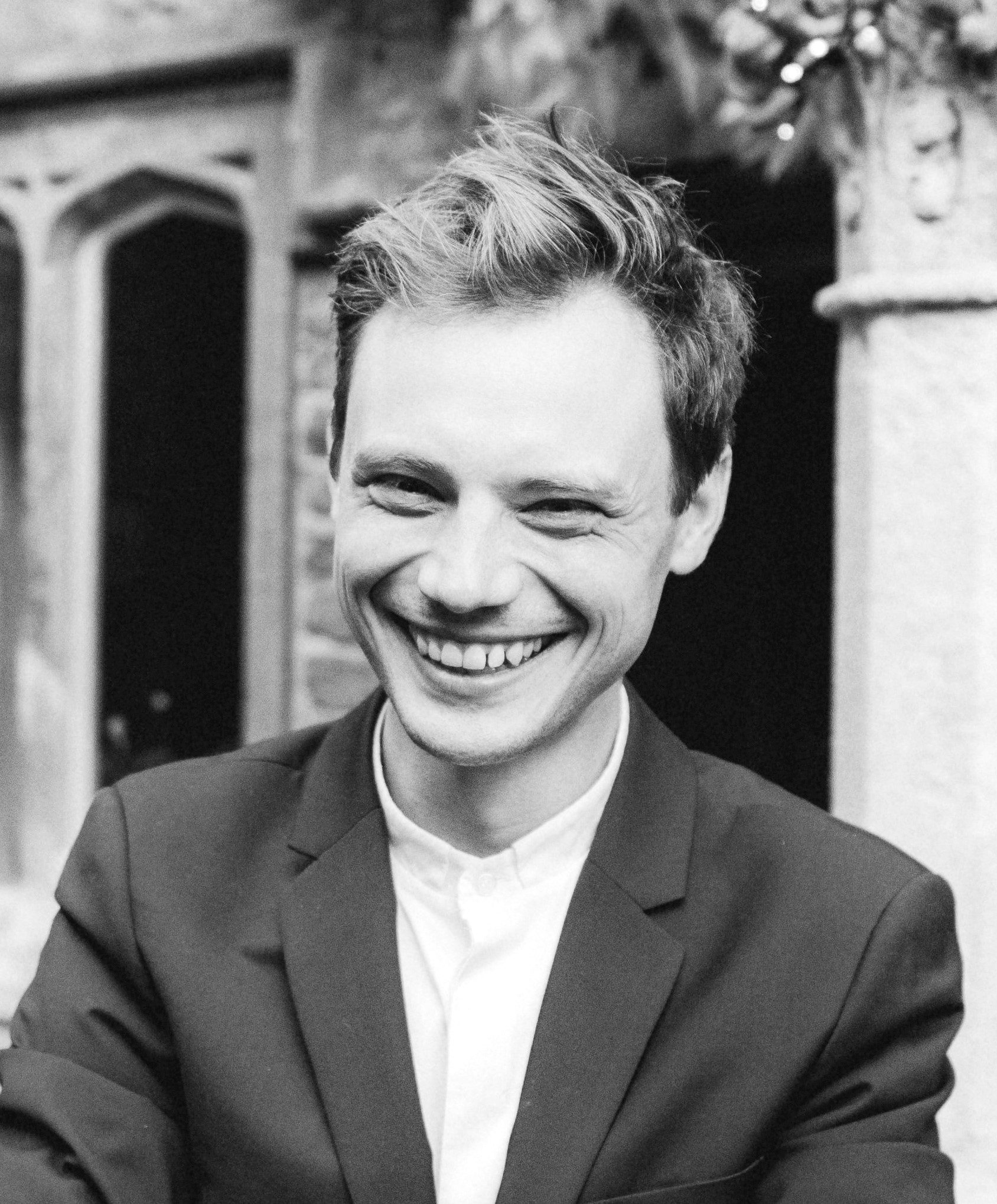 Black and white photo of a smiling white man in a blazer and white shirt