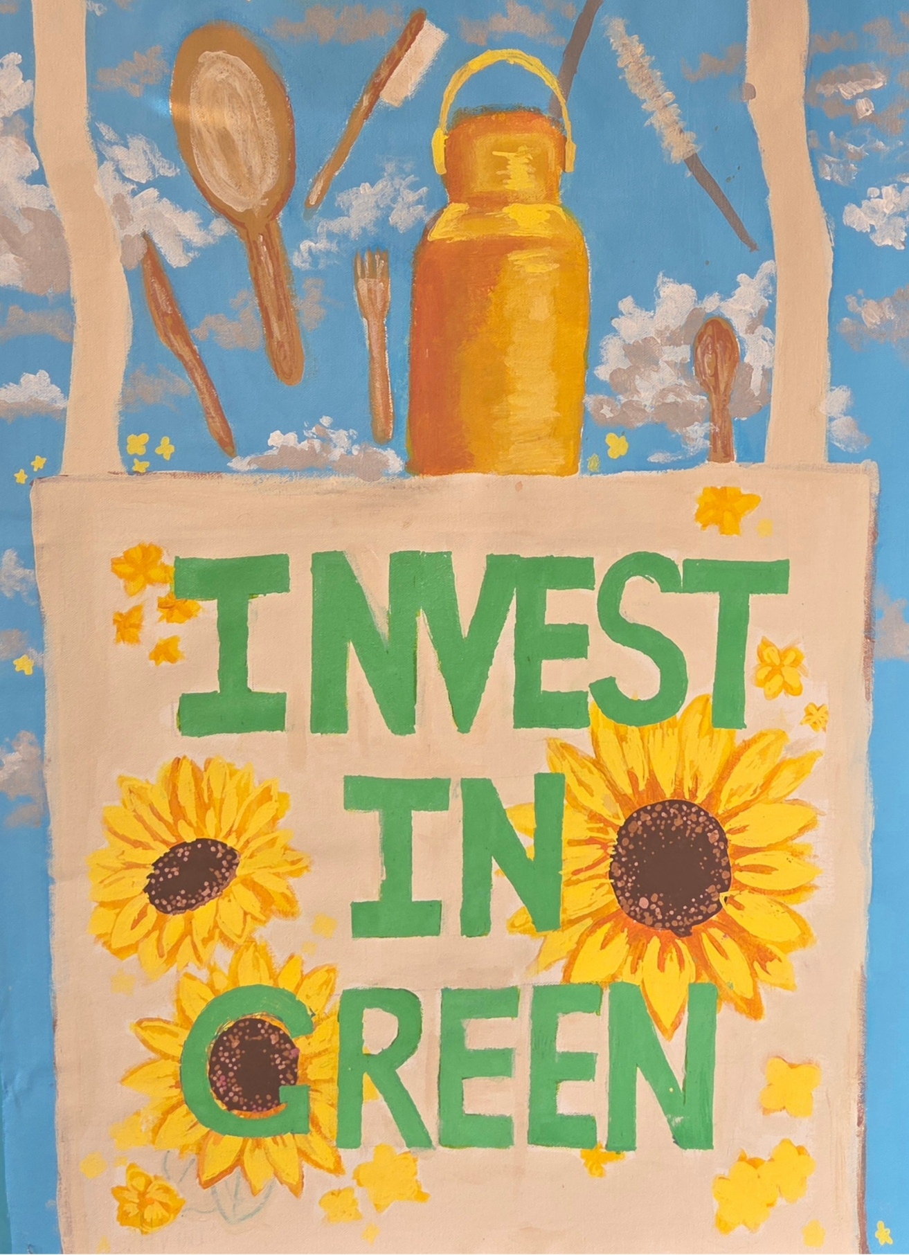 Over a bright cloudy blue sky is a tote bag with sunflowers and the words "Invest in Green" embroidered. Out of the bag falls sustainable items: A reusuable water bottle, bamboo utensils and a bamboo toothbrush.